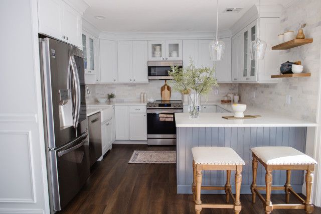 a kitchen with white cabinets and stainless steel appliances, along with two stools in front of the counter