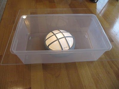 a plastic container with a cake in it on a wooden floor next to a table