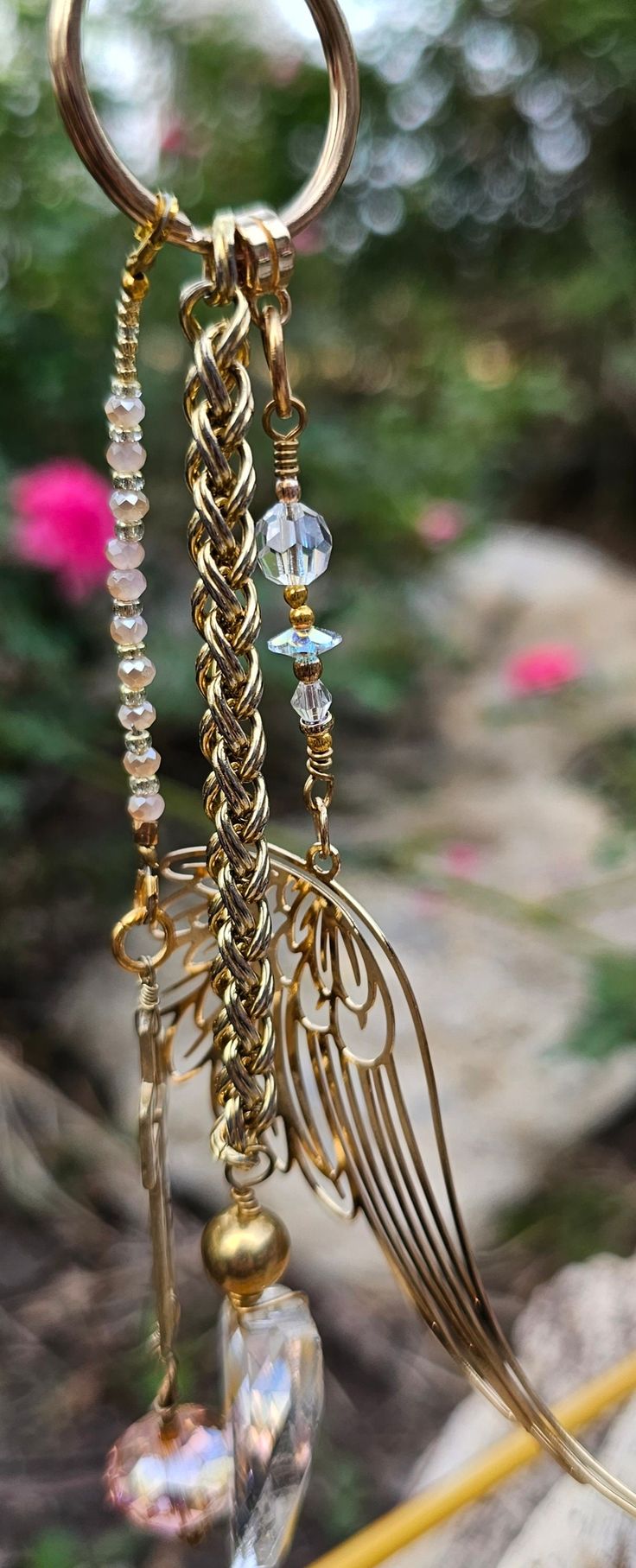 a golden wind chime with crystal beads and angel wings hanging from it's side