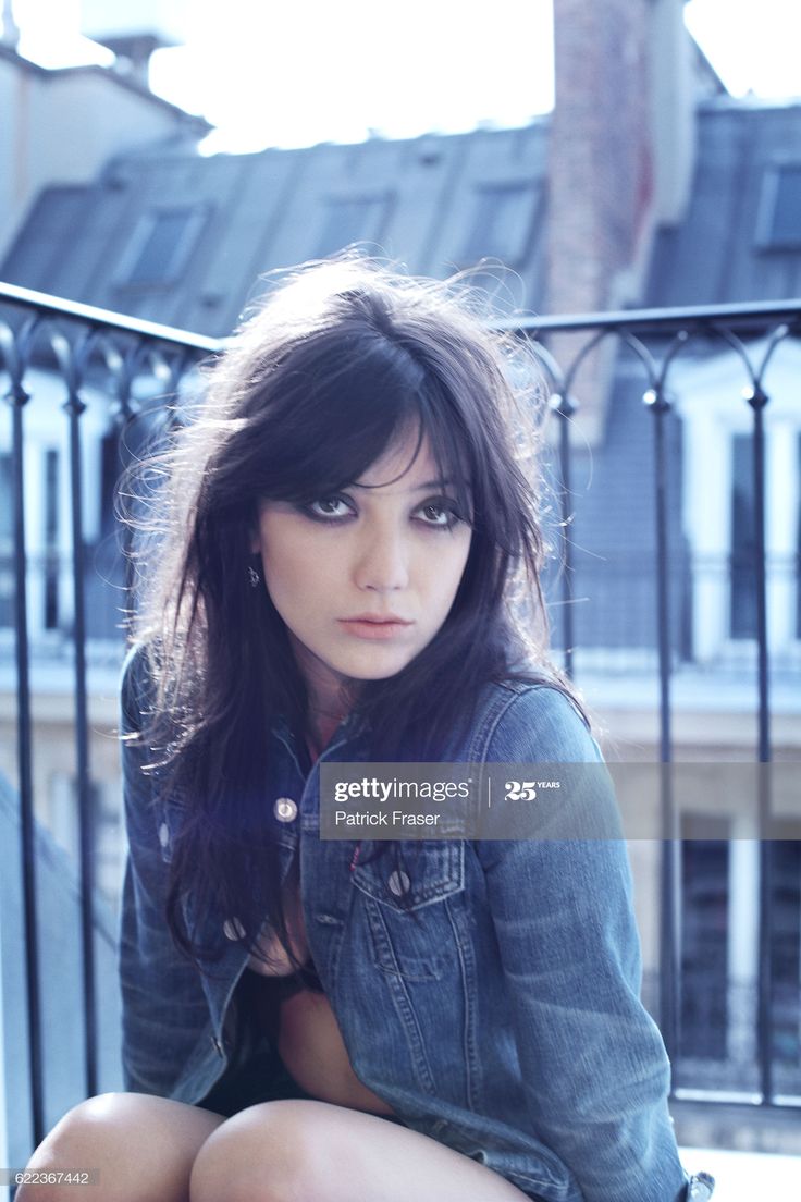 a young woman sitting on the ground with her legs crossed and looking at the camera