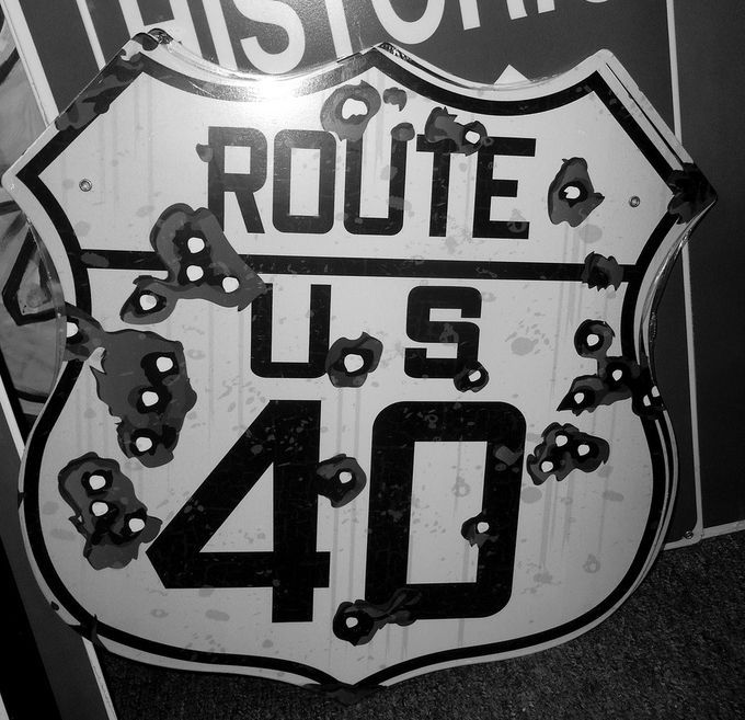 a black and white photo of an old route sign with the words route us 40 painted on it