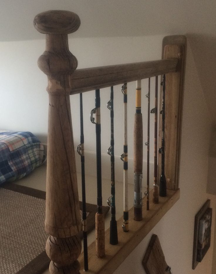 an old wooden banister with fishing rods on the bottom and sides, next to a bed