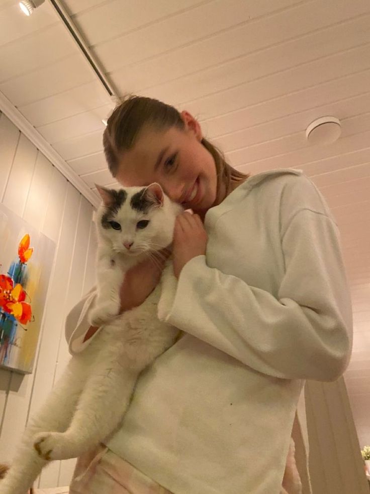 a woman holding a white cat in her arms