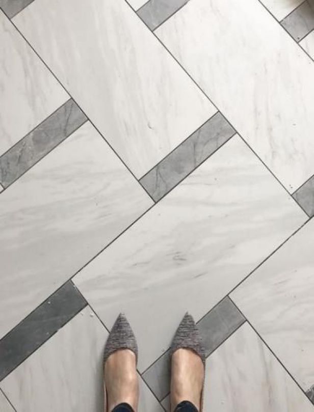 a person standing on a tiled floor with their feet up in the air and wearing gray shoes