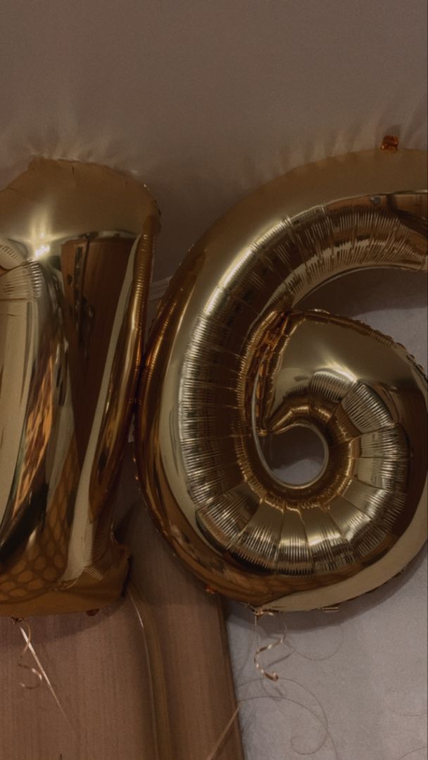 the number six is made out of gold foil and sits next to some other balloons