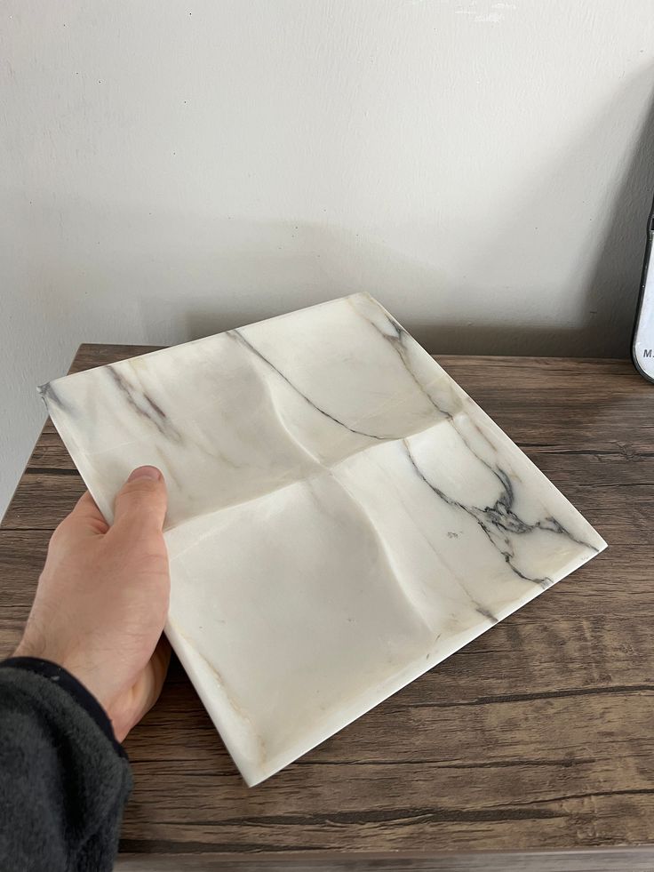 a person is placing marble tiles on top of a wooden table next to an alarm clock