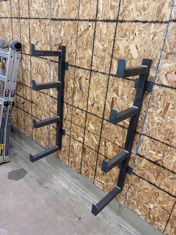 two ladders leaning against a wall with plywood behind them