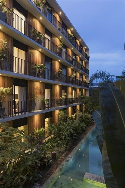 an apartment building at night with lights on the balconies and plants in front