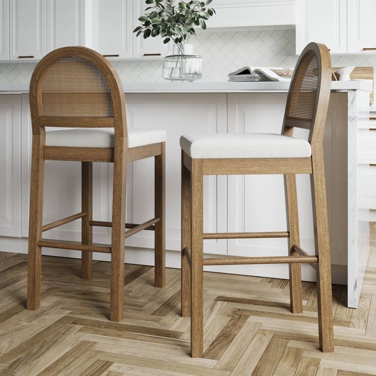 two wooden stools sitting next to each other in a kitchen with white cabinets and wood flooring