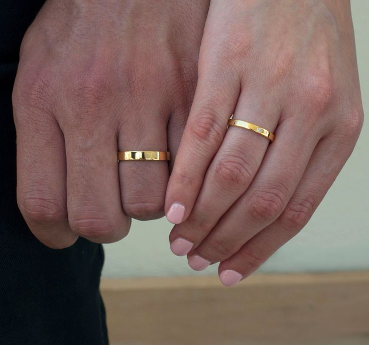 two people holding hands with gold rings on their fingers