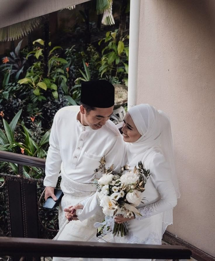 a man and woman standing next to each other on stairs with flowers in their hands