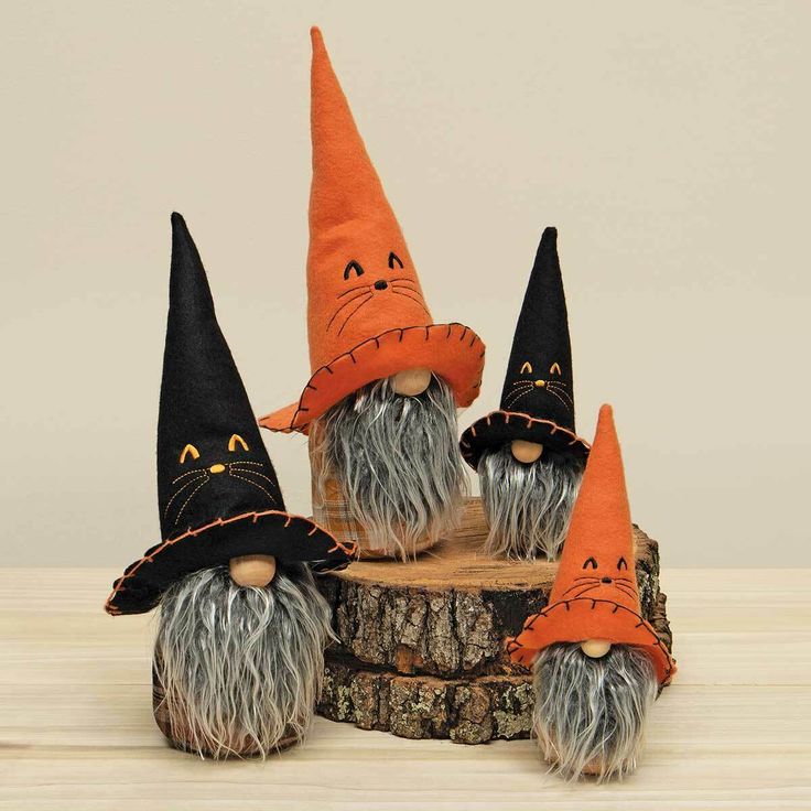 three orange and black gnomes sitting on top of a tree stump