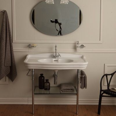 a white sink sitting under a bathroom mirror next to a black chair and wall mounted faucet