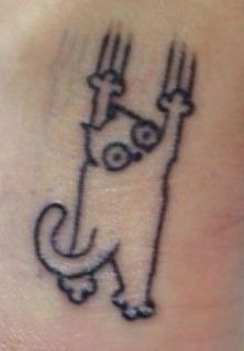 a small cat tattoo on the side of a woman's right leg, with two forks sticking out of it