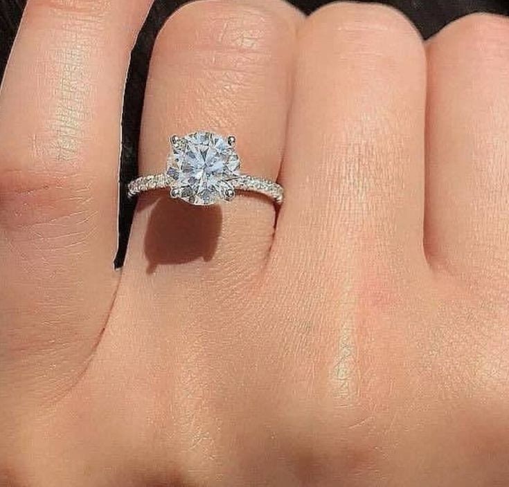 a woman's hand with a diamond ring on top of her finger and an engagement band