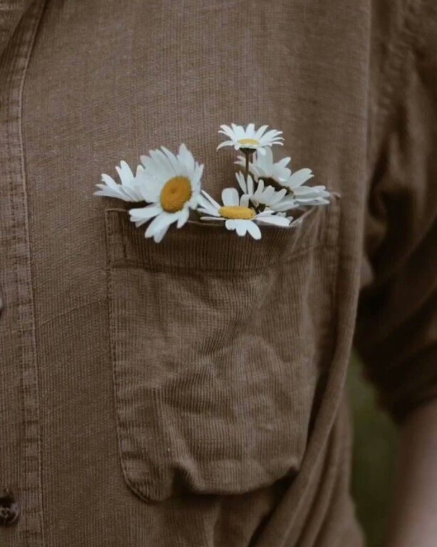 a person wearing a brown shirt with white flowers in the pocket