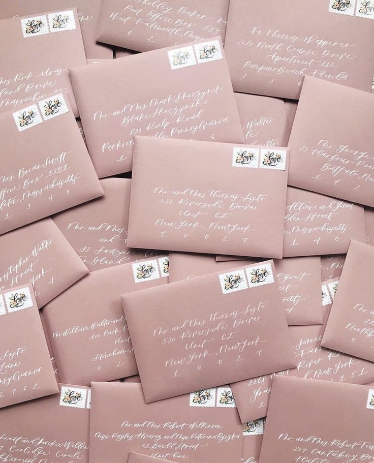 pink envelopes with white calligraphy are piled up in a pile on top of each other