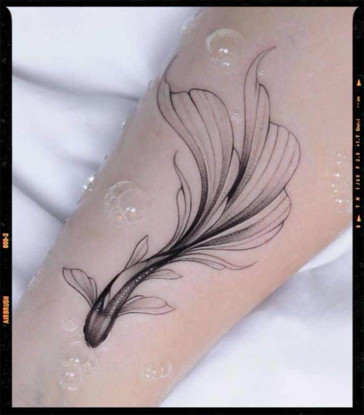 a black and white photo of a woman's arm with a feather tattoo on it