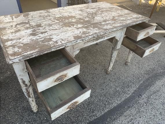 an old wooden table with drawers on the top and bottom, sitting in front of a building