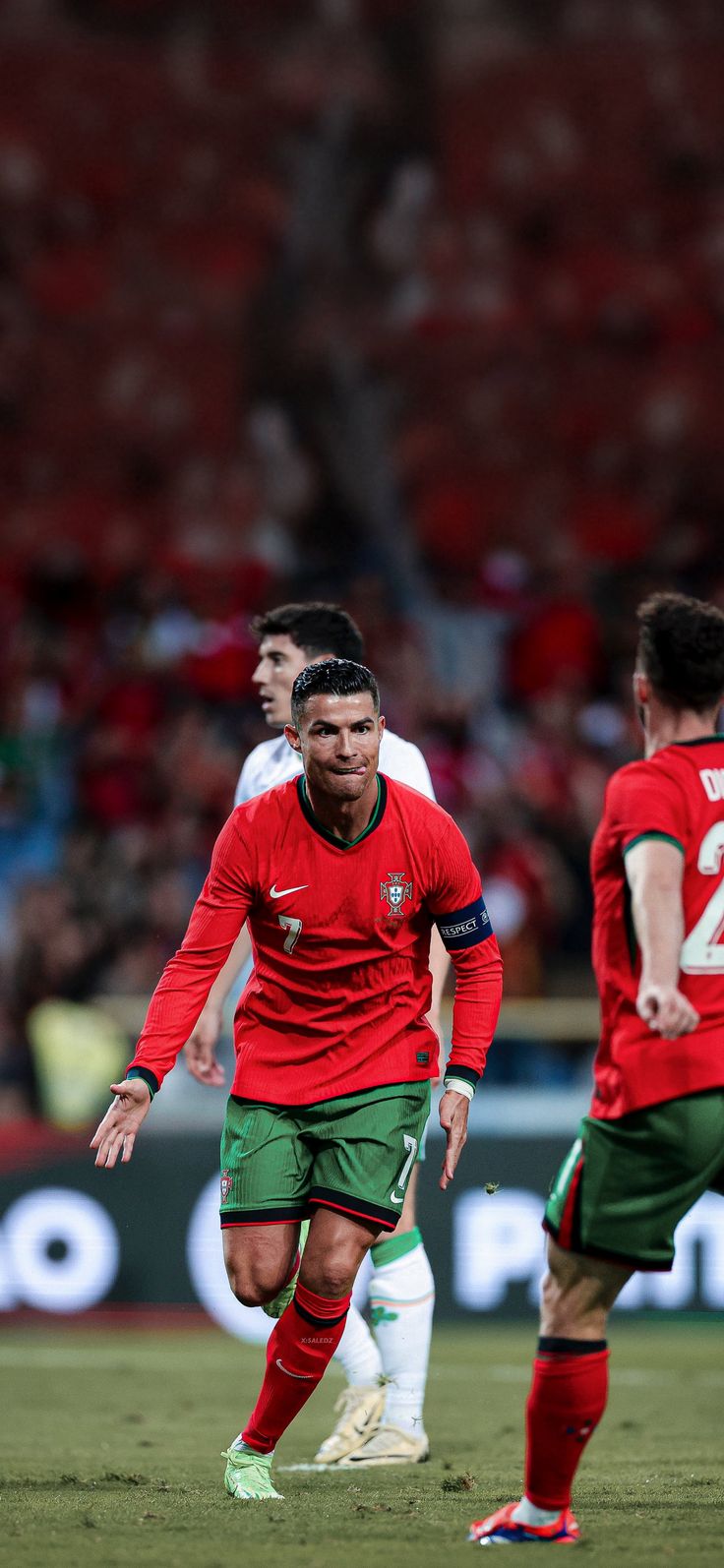 two soccer players in red and green uniforms are playing on the field with one another