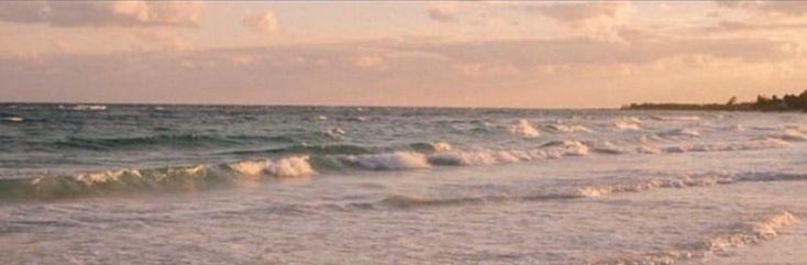 the waves are crashing on the beach at sunset