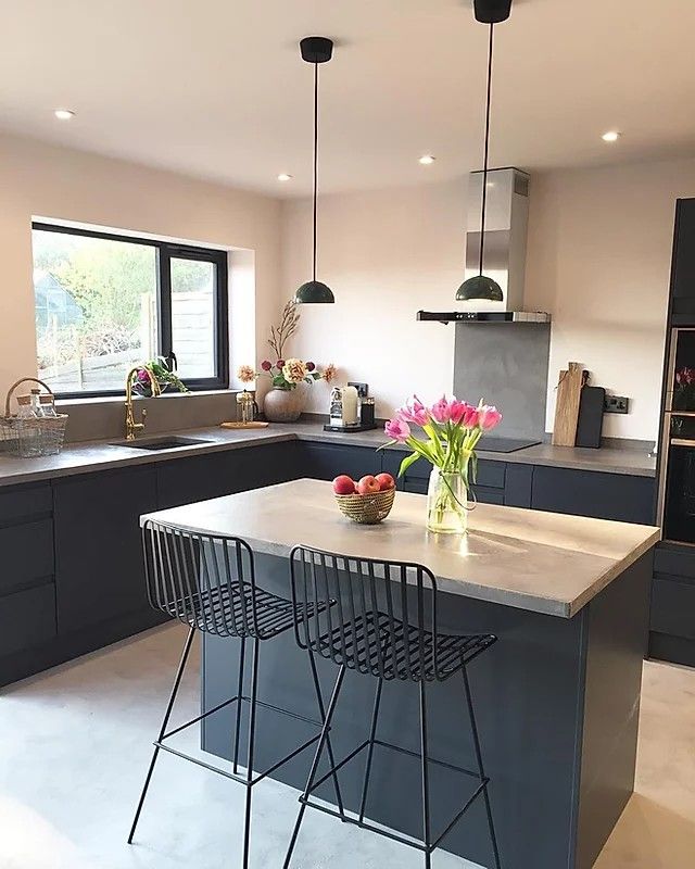 a kitchen with two bar stools in front of the counter and an island that has flowers on it