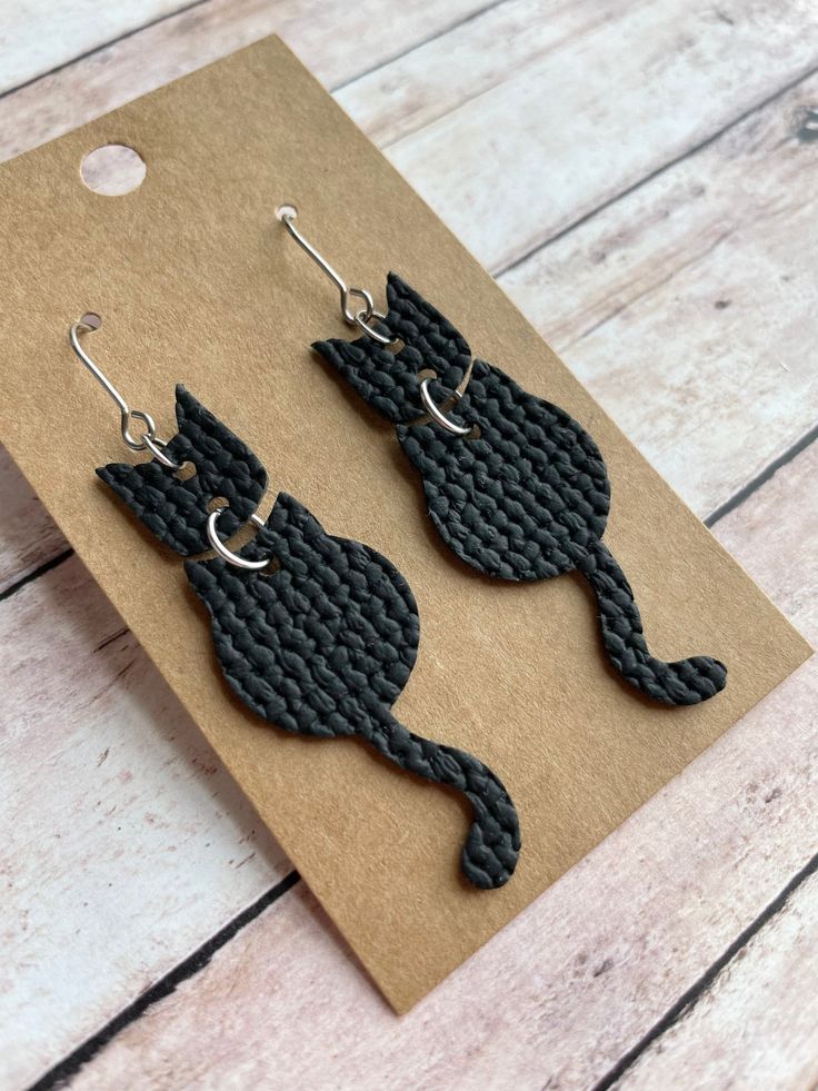 The cutest cat earrings! Made with stainless steel earring findings and faux leather (single-sided).  Each pair of earrings will be slightly different because of the variability in the faux leather pattern.  2.625 inches long by .625 inches wide. Free shipping on orders $35 and over! Warning: Choking Hazard. Small Parts. Keep out of reach of children under 5 years old. Fimo, Leather Ear Rings Diy, Fake Leather Earrings, Leather Jewellery Diy, Faux Leather Gifts, Leather Cricut Earrings, Faux Leather Halloween Earrings, Faux Earring Ideas, Halloween Leather Earrings