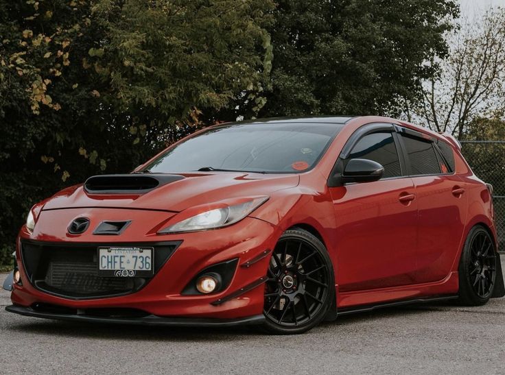 a red sports car parked in front of some trees