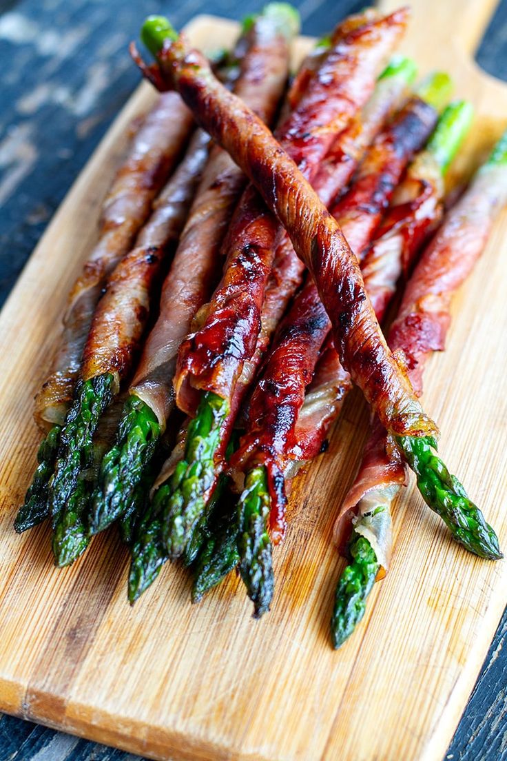 bacon wrapped asparagus on a wooden cutting board