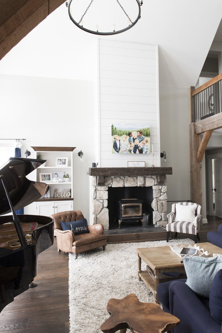 a living room filled with furniture and a piano in front of a fire place on top of a hard wood floor