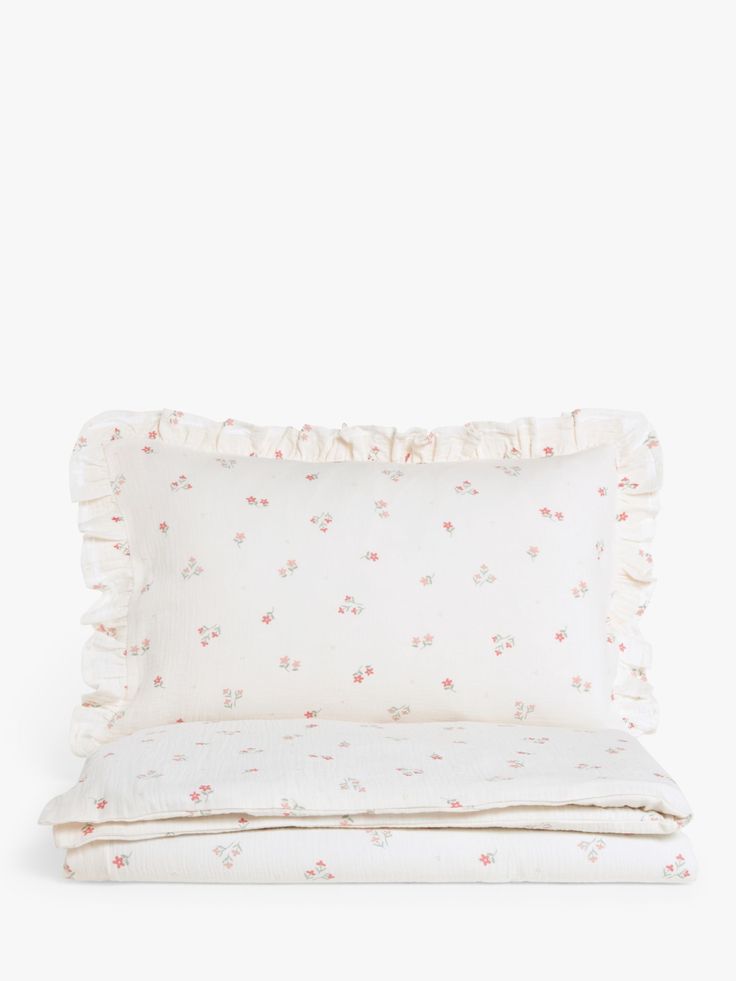 a white pillow with pink flowers and ruffles on the bottom, sitting next to a