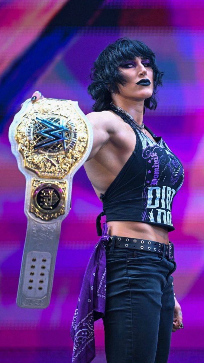 a female wrestler holding a wrestling belt on stage