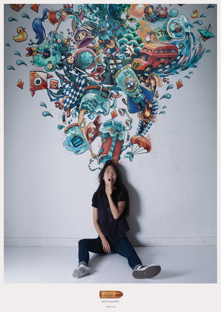 a woman sitting on the floor in front of a wall with an artistic mural behind her