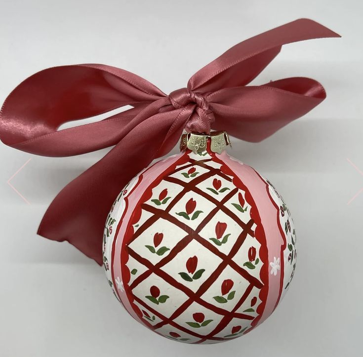 a red and white ornament with a bow on it