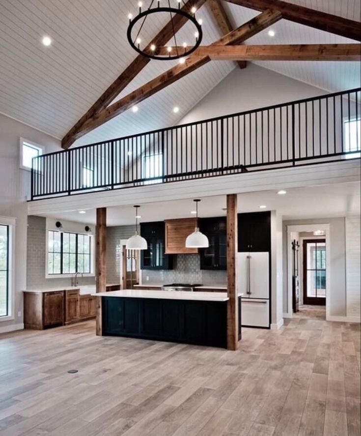 an open concept kitchen and living room with wood flooring, white walls and beams