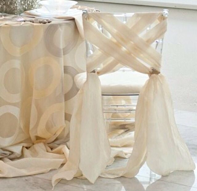 the table is covered with sheer curtains and has a vase on it next to it