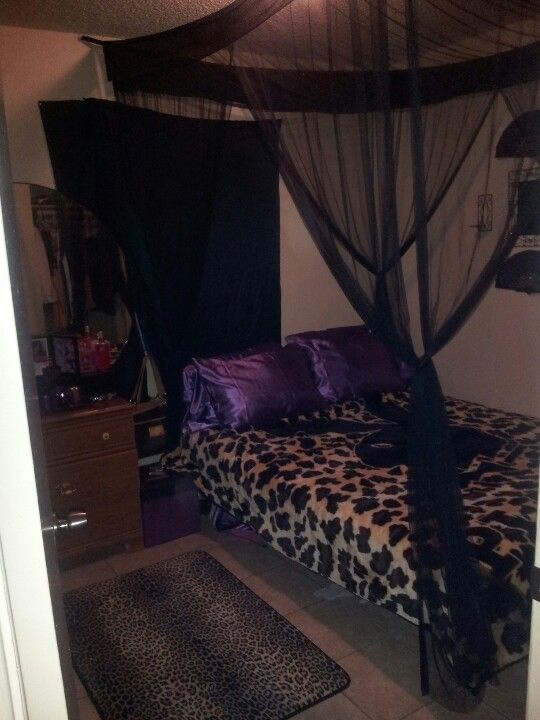 a leopard print bed with black canopy and purple pillows