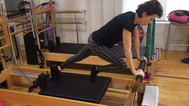 a woman is doing exercises on an exercise machine in a room with wooden floors and stairs