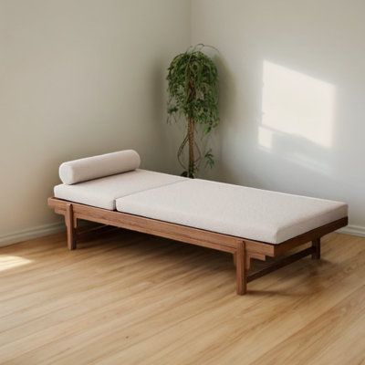 a bed sitting on top of a hard wood floor next to a potted plant