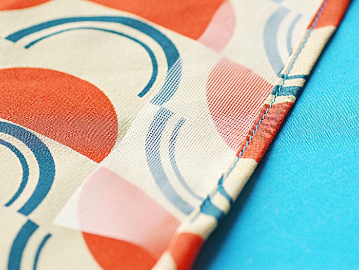 an orange, blue and white fabric with circles on it's side is folded