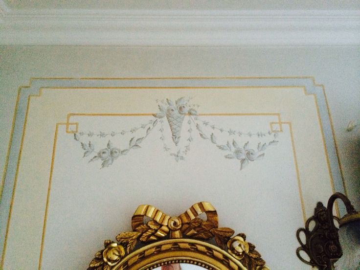 an ornate gold framed mirror on the wall in a room with white walls and ceiling