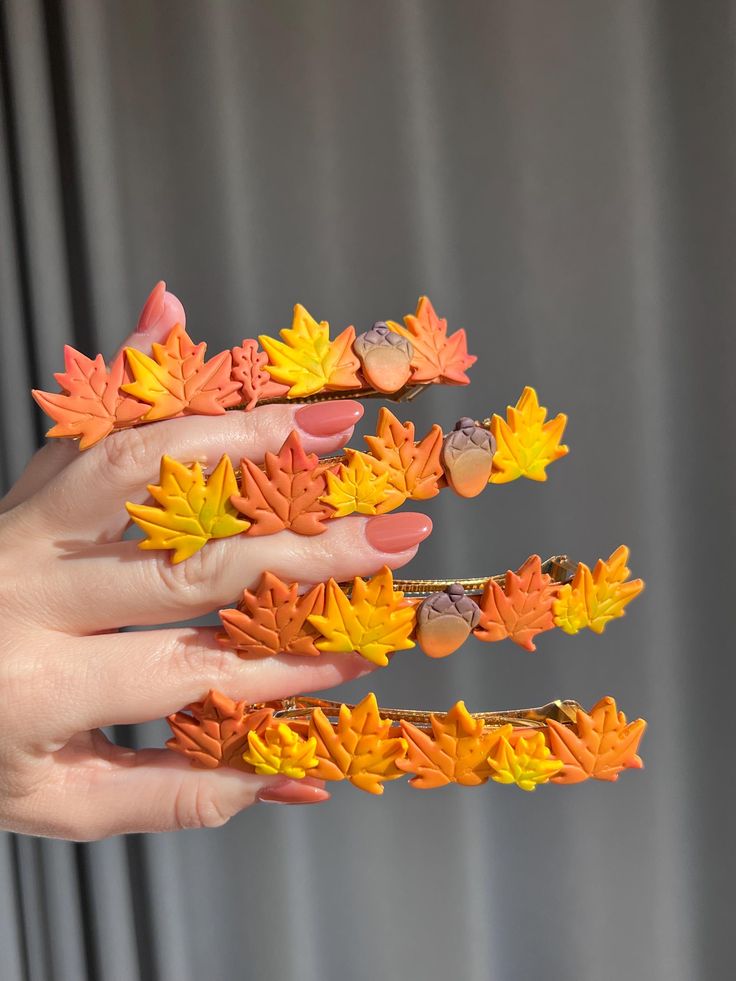 a woman's hand holding three fake autumn leaves