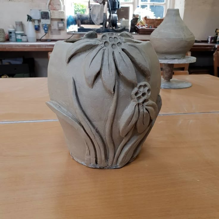 a vase sitting on top of a wooden table next to other pottery items in the background