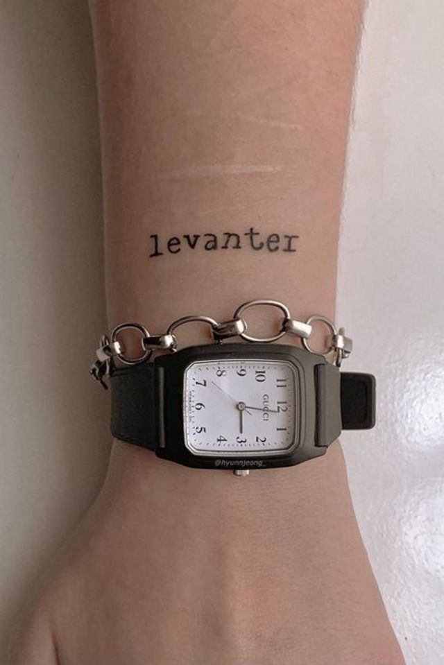 a wrist tattoo with the word levianter written on it and a watch attached to it