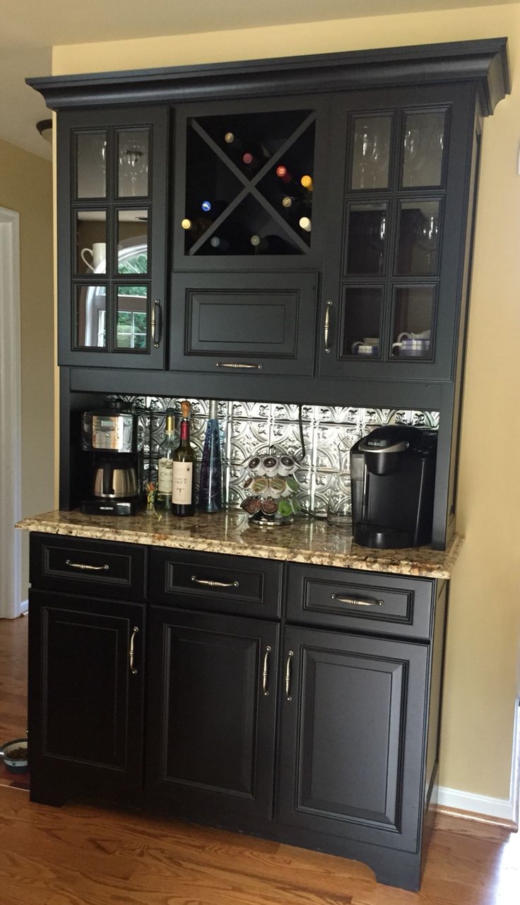 a kitchen with black cabinets and marble counter tops, wine glasses on the cabinet doors