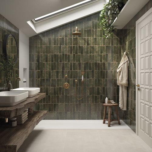 a bathroom with two sinks and a walk in shower next to a large tiled wall