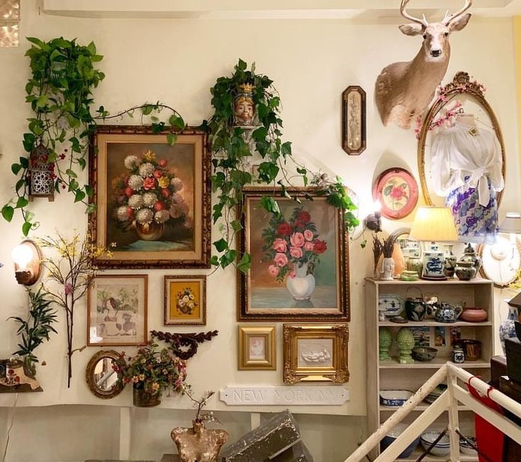 there are many pictures on the wall with flowers in vases and deer heads above them