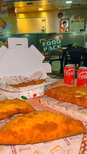 some food is laying out on a table in front of sodas and other items