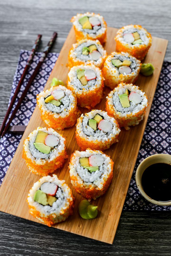 sushi rolls with avocado and cucumber on a wooden cutting board