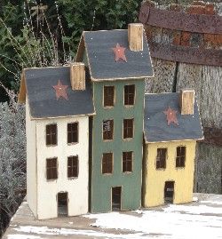 three small wooden houses sitting on top of a snow covered ground next to a fence